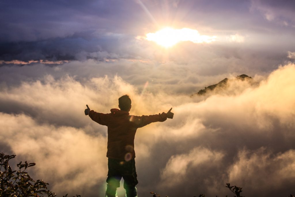 man doing thumbs up on mountain