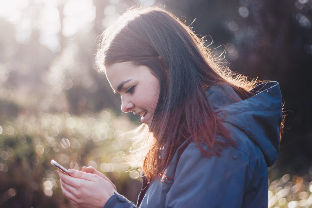 Woman in a blue hoodie looking at her phone