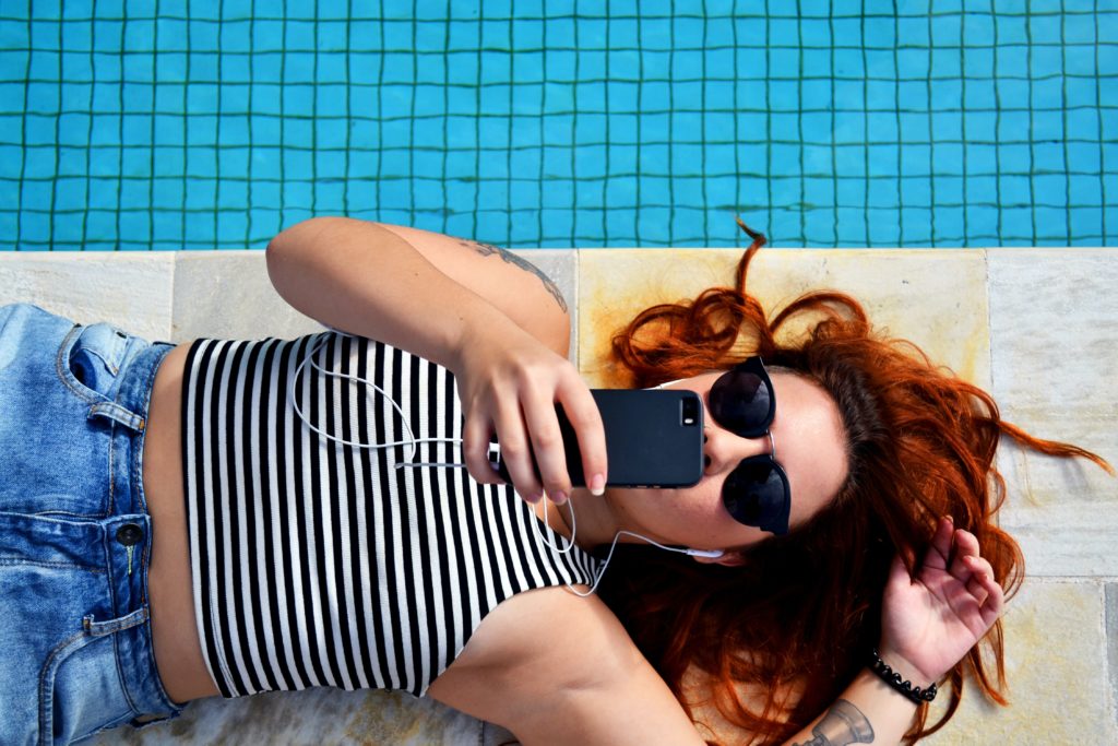 Woman watching video on her phone by a pool