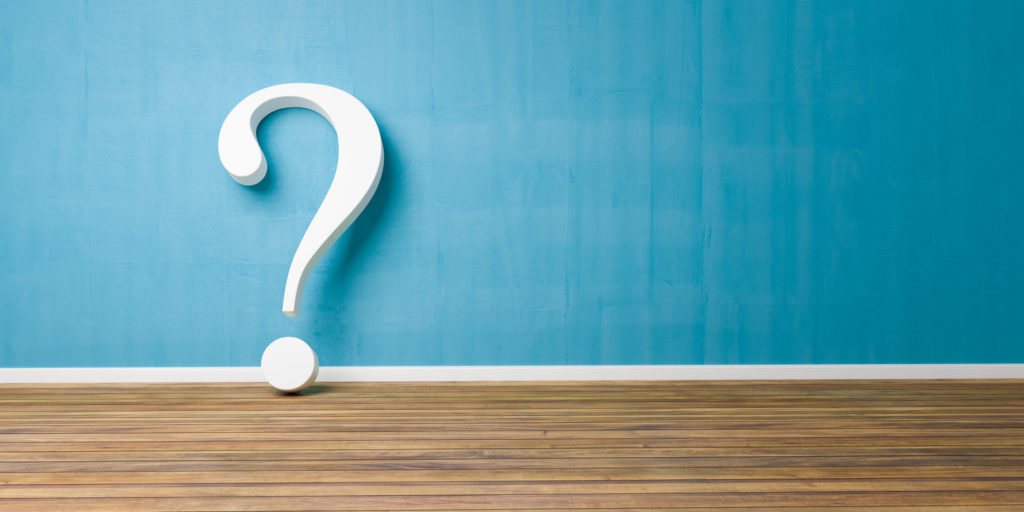 White question mark on a wooden floor against a blue wall