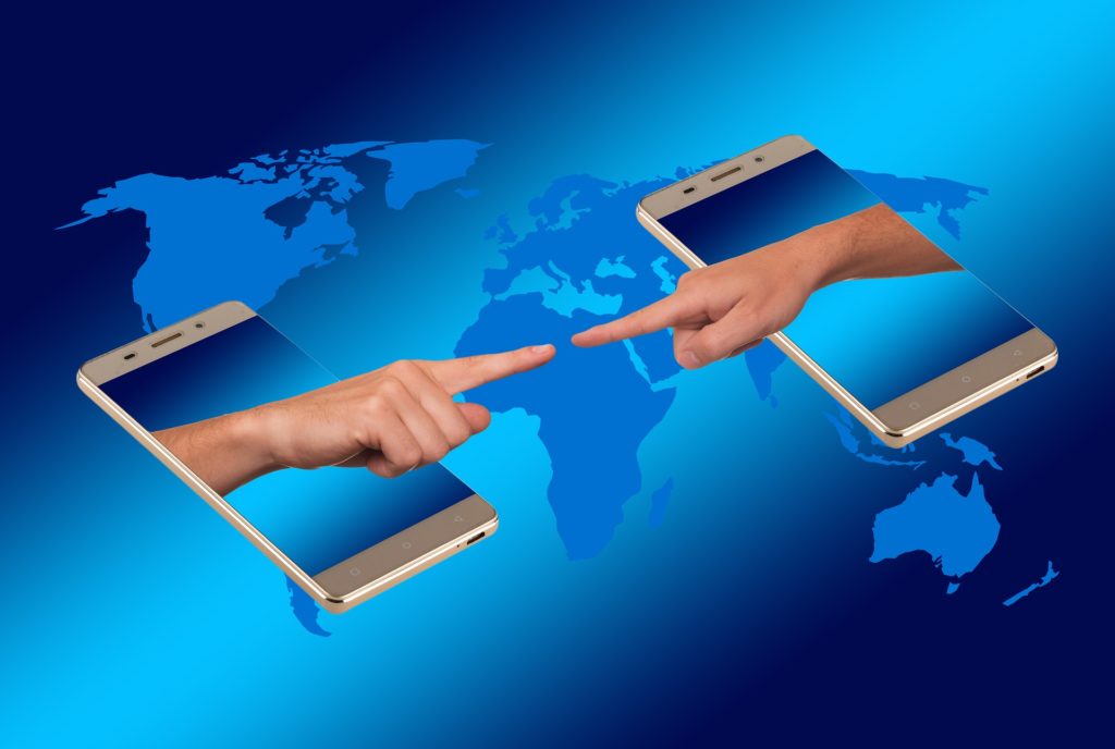 digital image of two smartphones with hands emerging to touch fingers