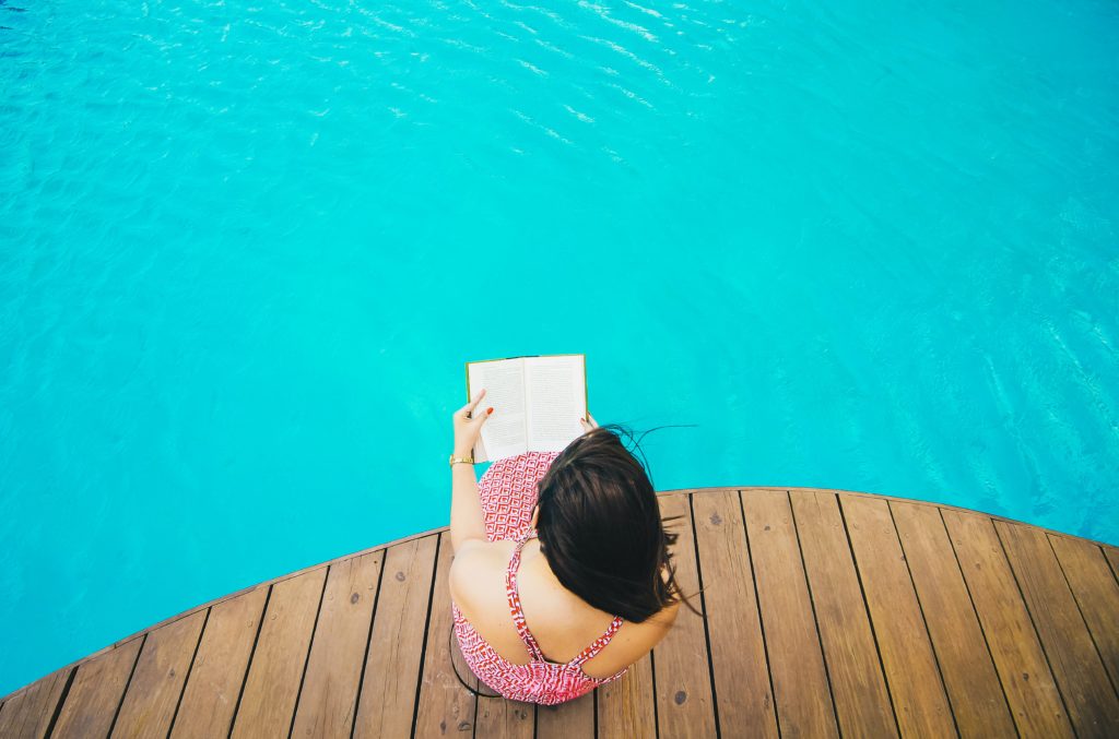Woman reading a book on the edge of the water