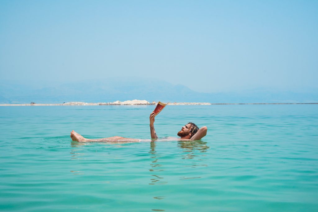 Man reading while lying on his back in the Dead Sea