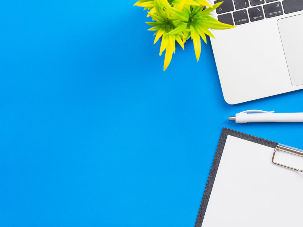 Minimal workspace - creative flat lay of your desktop. Office table top view with laptop. View from above in blue