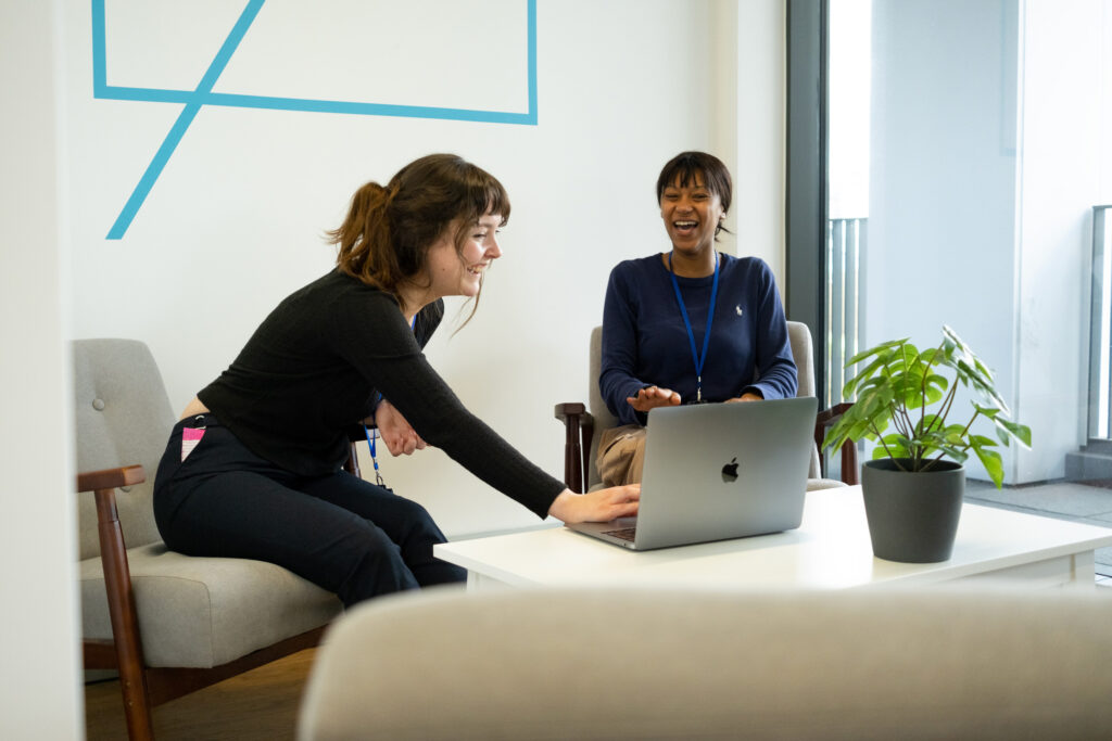 Two seated women looking over a laptop