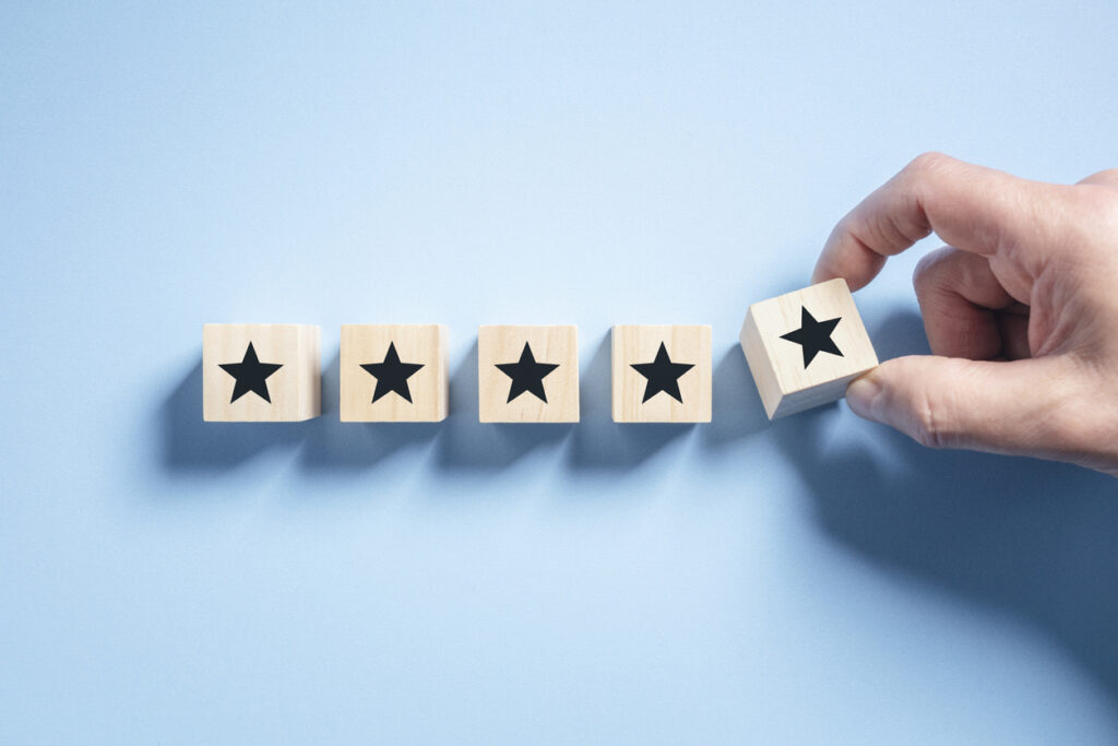 Customer experience feedback rate satisfaction experience five star rating placing wooden blocks on blue background