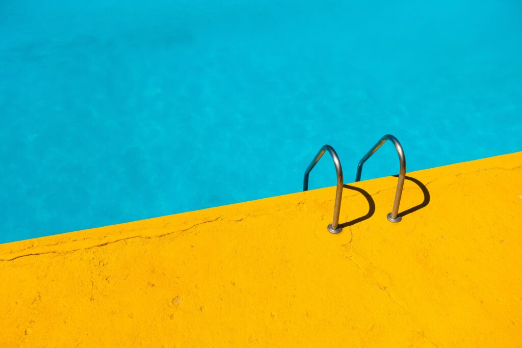 Metal pool steps with a contrasting turquoise and yellow background