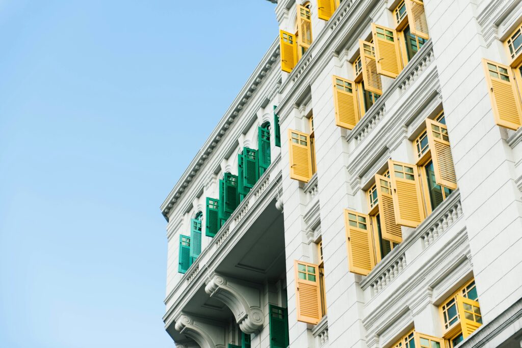 White building with teal and yellow shutters hanging open