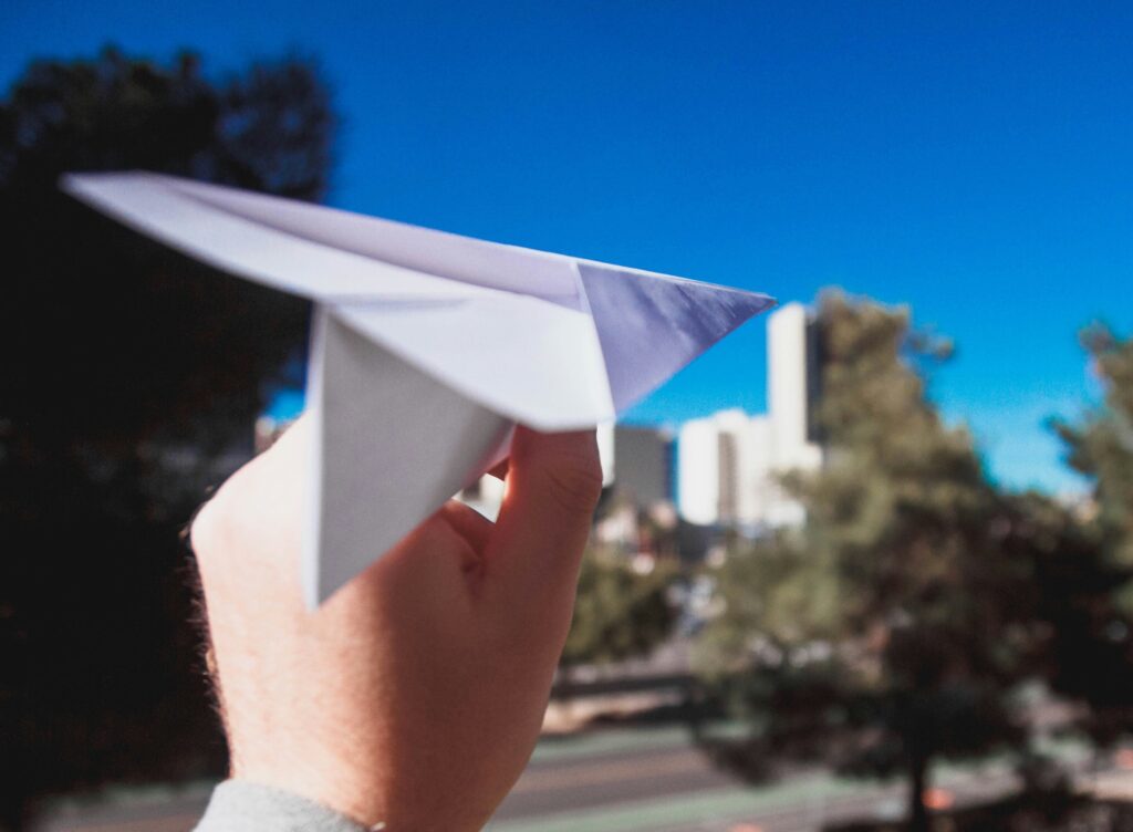 Hand holding paper plane, ready to launch